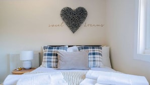 A neatly made bed with a heart-shaped wall decoration and a sign that reads "sweet dreams". - Mary Street Seaside Home in Stonehaven Aberdeenshire (Stonehaven)