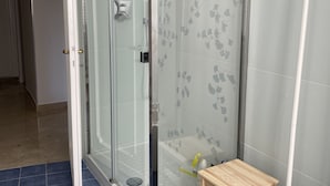 A modern bathroom with a glass shower enclosure, a wooden stool, and a white sink. - Spacious rooms in the center of Rome (Roma)