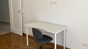 A room with a white desk and chair, a wooden herringbone floor, and a white door. - Spacious rooms in the center of Rome (Roma)