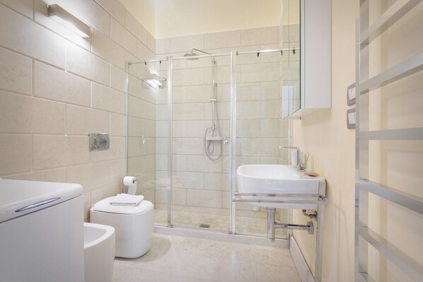 A modern bathroom with a glass-enclosed shower, a white sink, and a toilet.