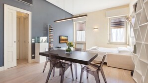 Ein modernes Wohnzimmer mit Esstisch, Stühlen, einer Couch und einem Bücherregal.