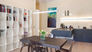 Eine moderne Küche mit Essbereich, mit einem weißen Bücherregal, einer Vase mit Blumen und einem Gemälde an der Wand.