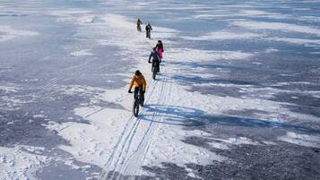 A group of people riding bicycles on a snowy surface.