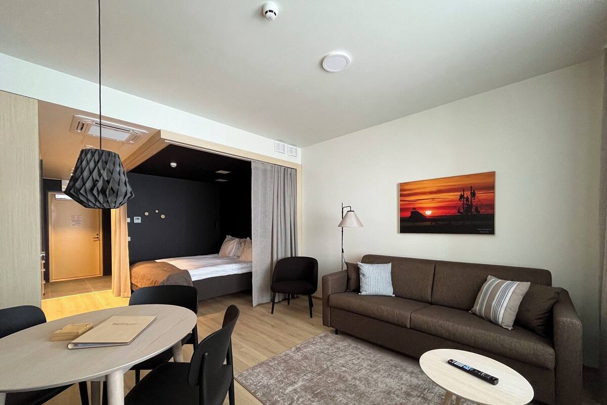 Ein modernes Hotelzimmer mit Bett, einer Sitzecke, einem Essbereich und einem Gemälde an der Wand.