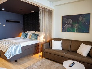 Quarto de hotel moderno com cama, sofá, mesa de centro e pintura da Aurora Boreal.