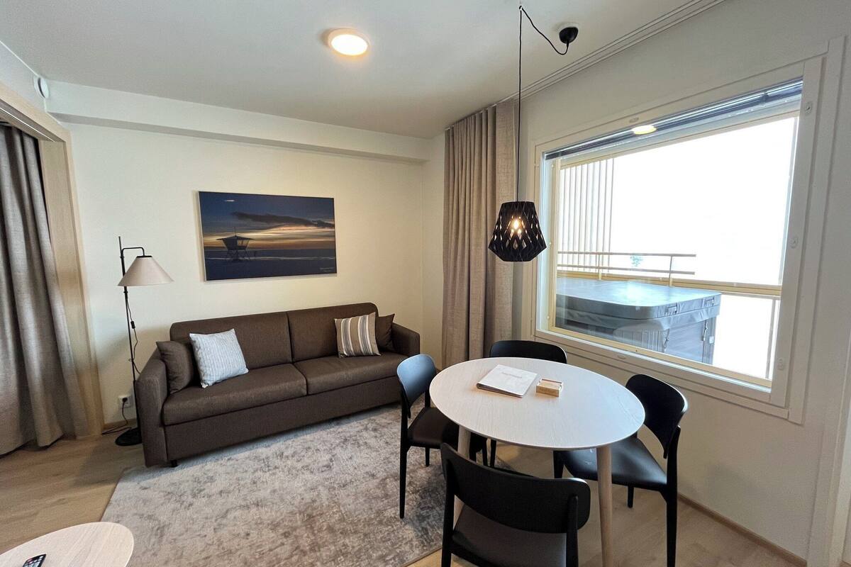 Ein modernes Wohnzimmer mit einer Couch, einem runden Esstisch und einem großen Fenster mit Blick.