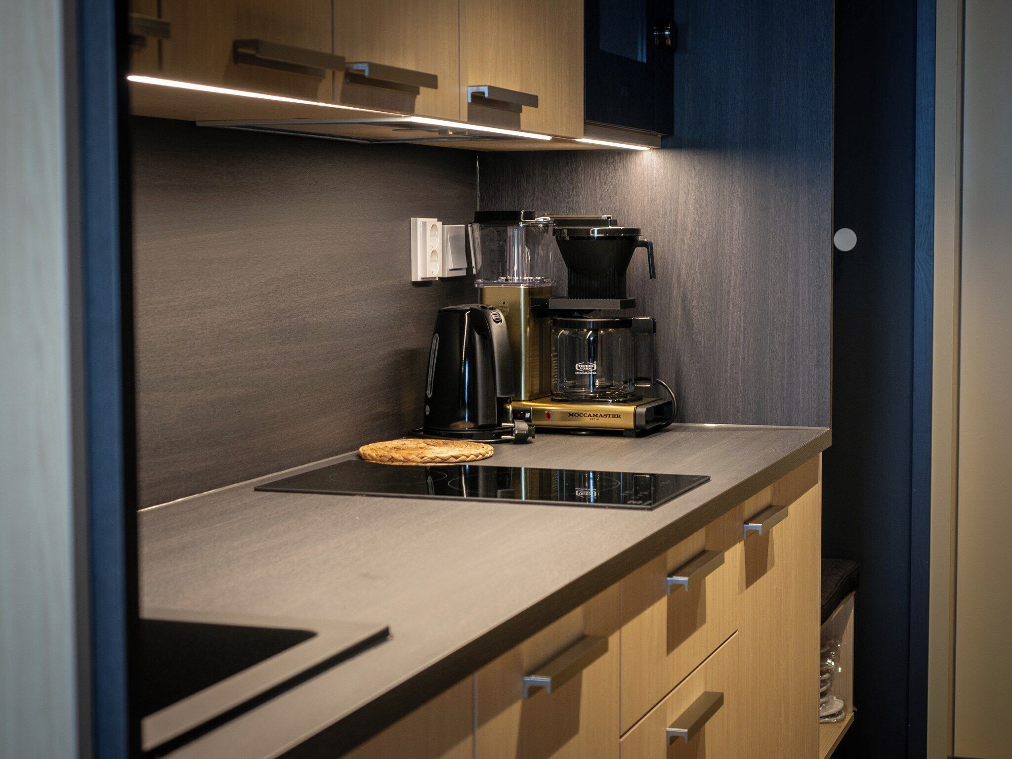 A modern kitchen with a built-in microwave, a coffee maker, and a glass carafe.