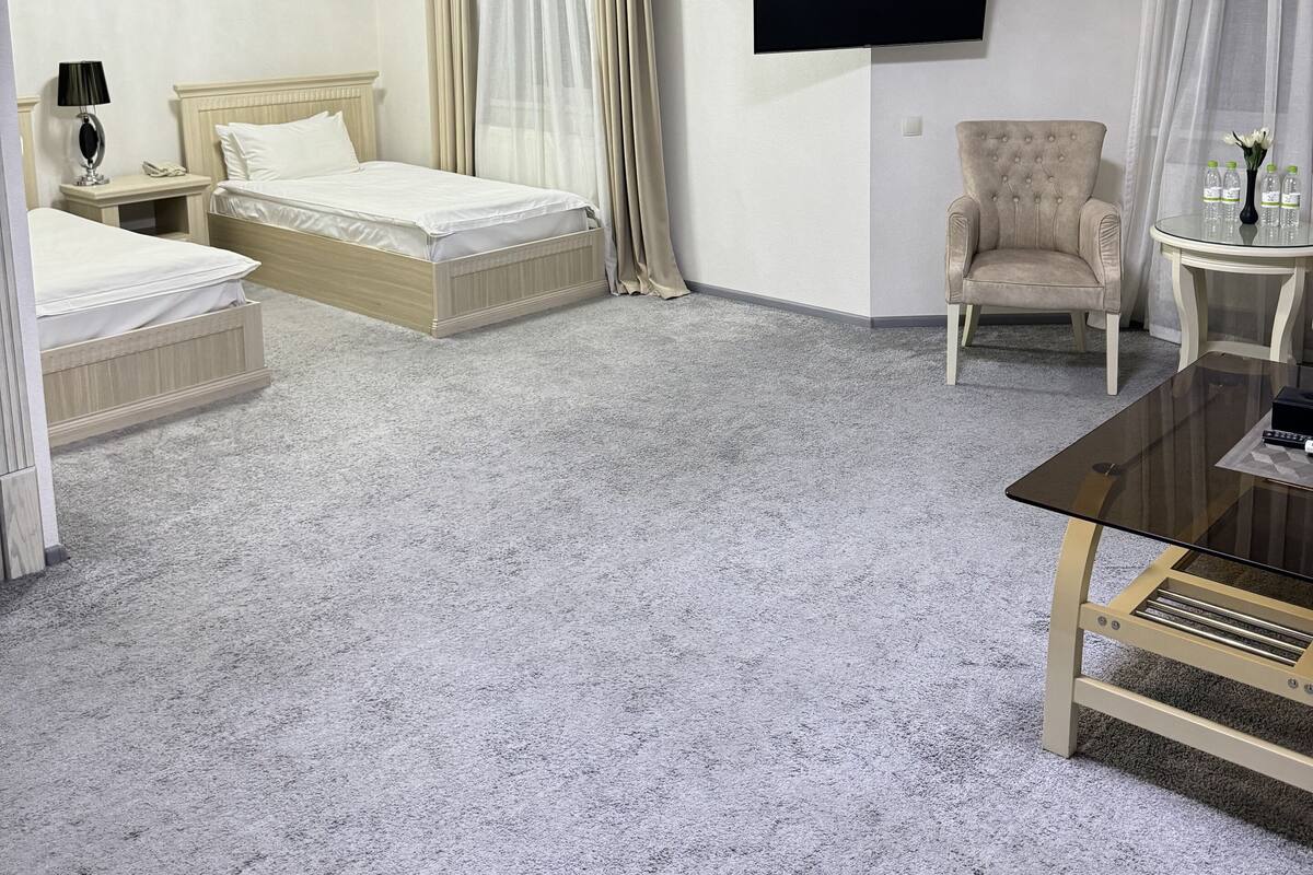 A hotel room with two beds, a chandelier, a flat-screen TV, a chair, and a small table.