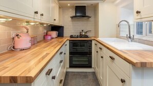 A compact kitchen with wooden countertops, a built-in oven, a gas stove, and a modern sink. - The Cottage (Poulton-le-Fylde)