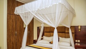 Una cama con dosel y pilares, con cabecera de madera y ropa de cama blanca.