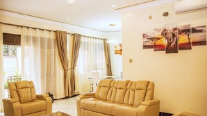 Un salón amplio con un sofá color beige, dos sillones y una mesa de centro de cristal.