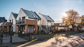 A modern residential building with a sloped roof, a gated entrance, and a staircase leading to a second floor.