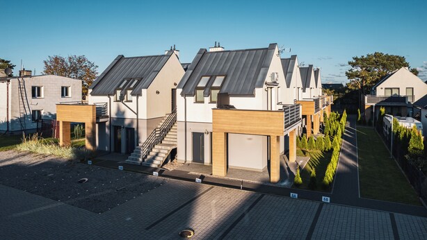 A modern residential complex with multiple houses, each featuring a sloped roof, a garage, and a small front yard.