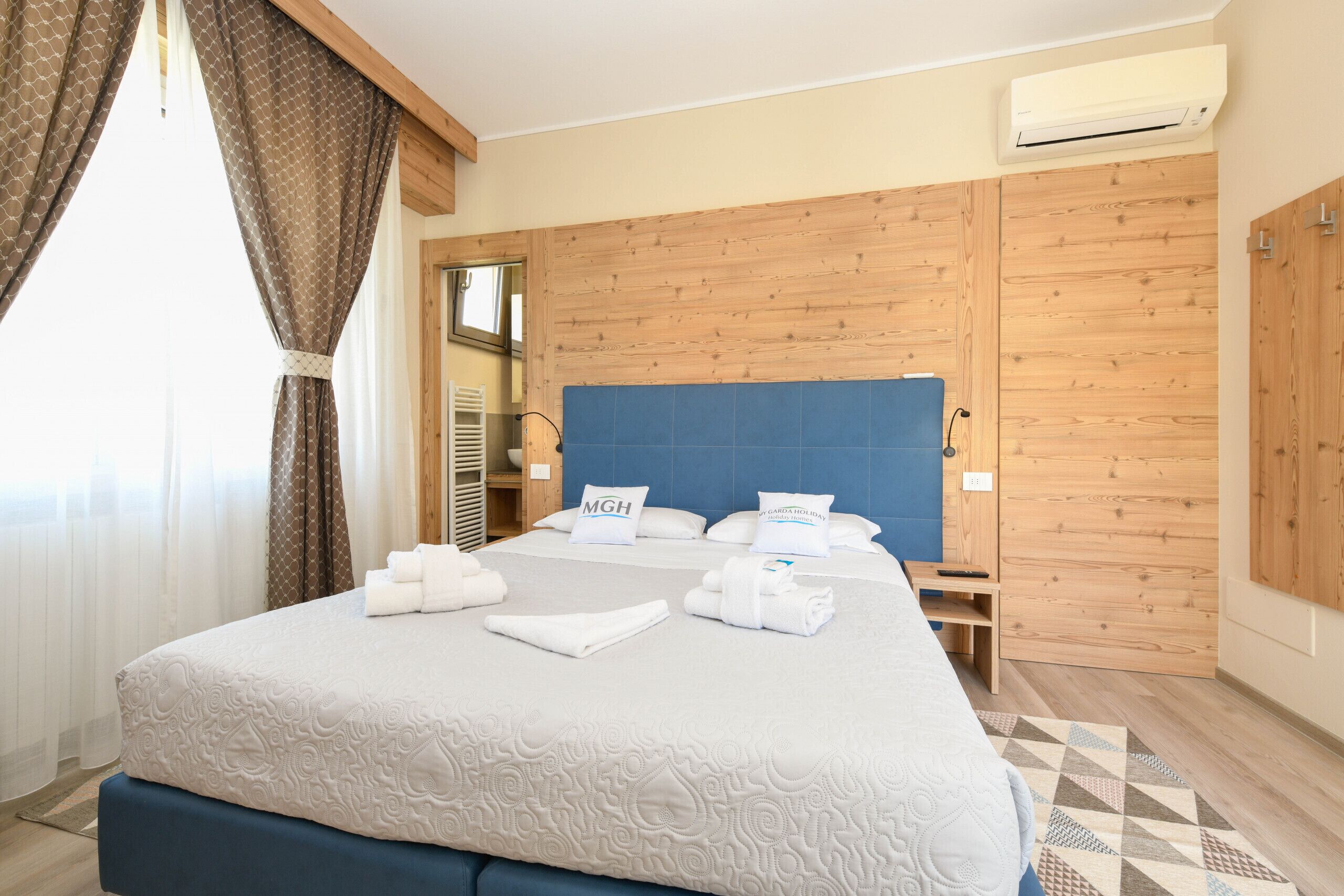 Ein Hotelzimmer mit einem großen Bett, einem Holzschrank und einer Klimaanlage.
