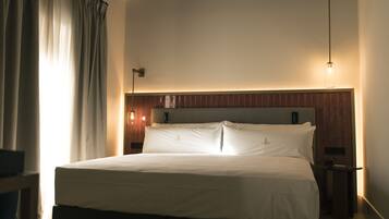 Una camera da letto con un letto grande, travi in legno a soffitto, un comodino e una lampada.