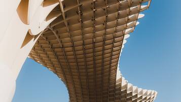 A modern architectural structure with a unique, curved design and a grid-like pattern on the upper part.