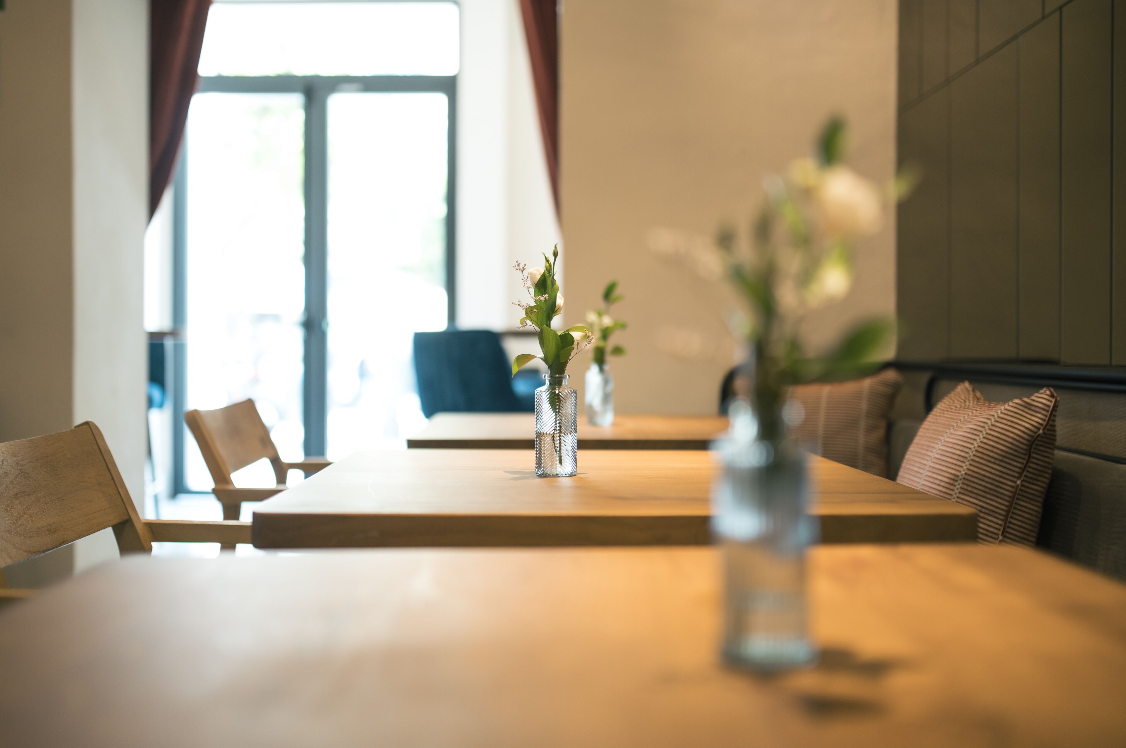 A dining area with a wooden table, chairs, and a vase with flowers.