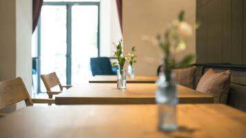 A dining area with a wooden table, chairs, and a vase with flowers.