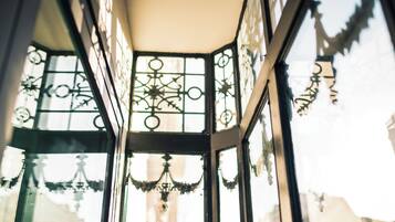 Un coin de pièce avec des grilles métalliques décoratives aux fenêtres et un lustre.