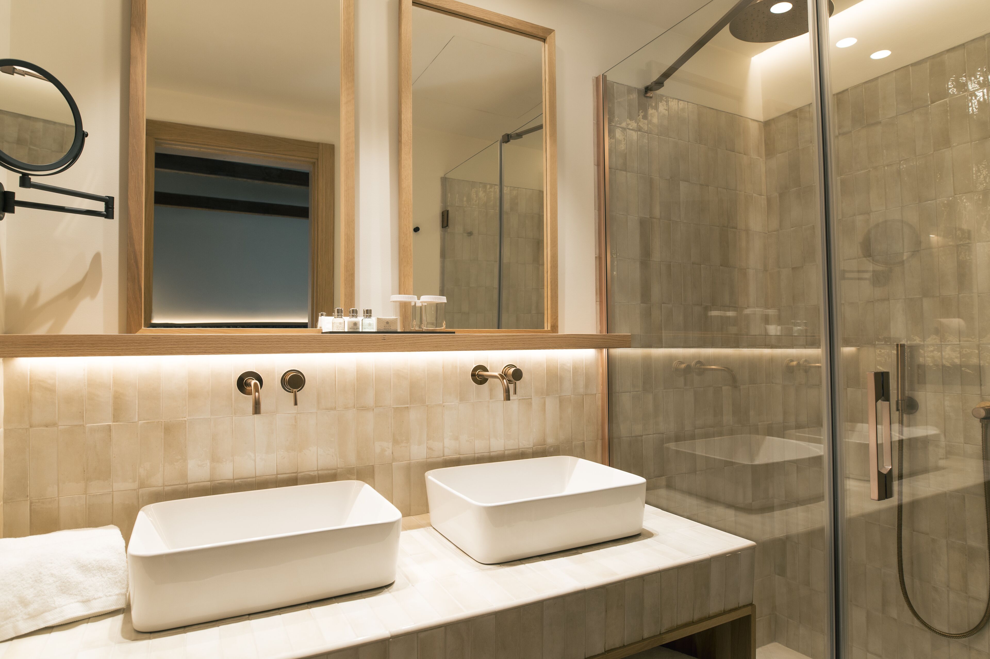 Ein modernes Badezimmer mit zwei rechteckigen Waschbecken, einem großen Spiegel und einer gläsernen Duschkabine.