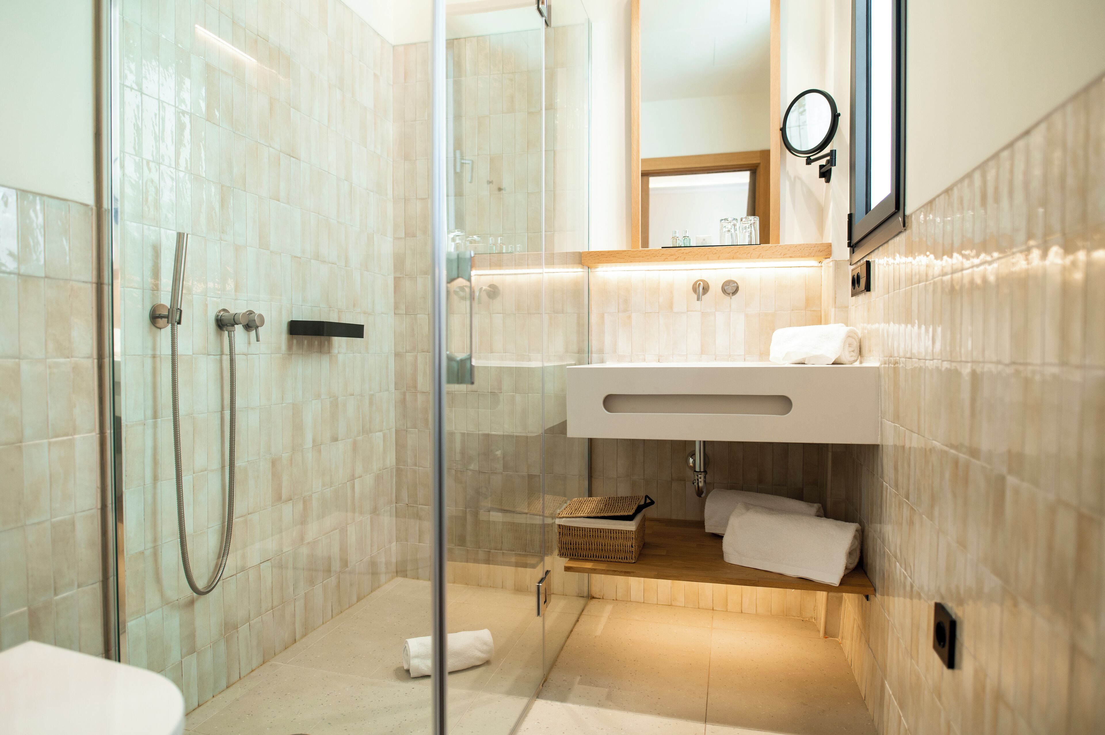 A modern bathroom with a glass-enclosed shower, a wooden vanity, and a mirror above the sink.
