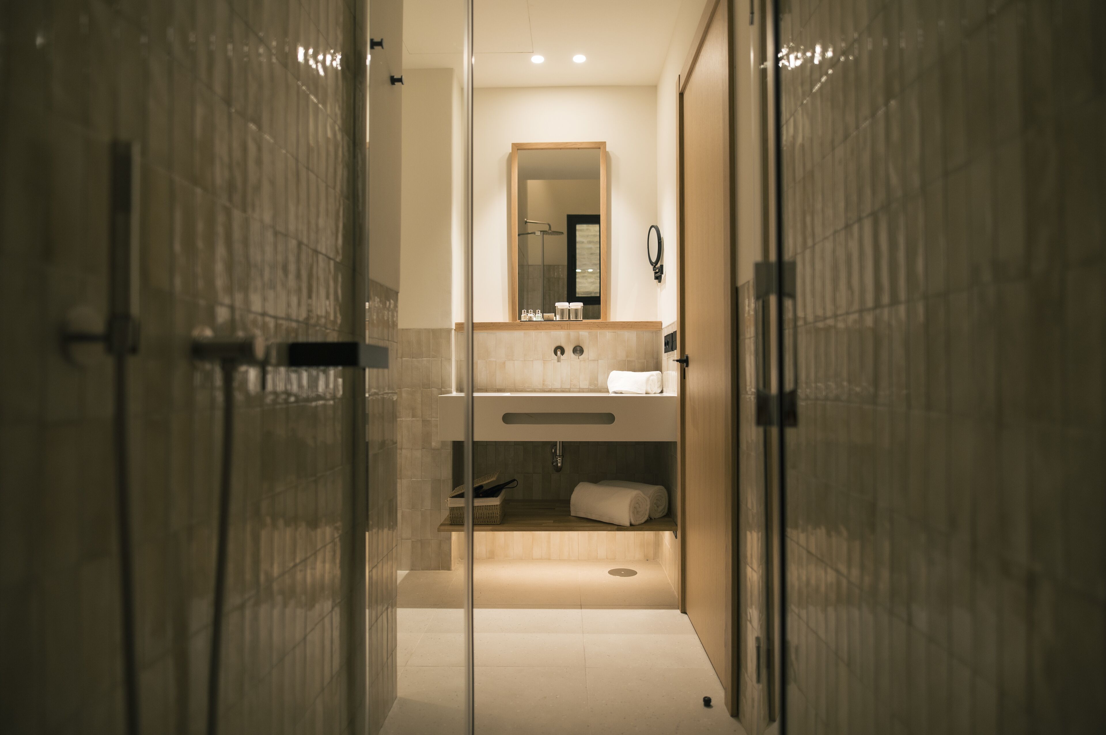 Une salle de bain moderne avec une douche à parois de verre, un meuble-lavabo en bois et un grand miroir.