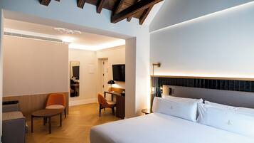 A hotel room with a large bed, a desk, a chair, and a television.