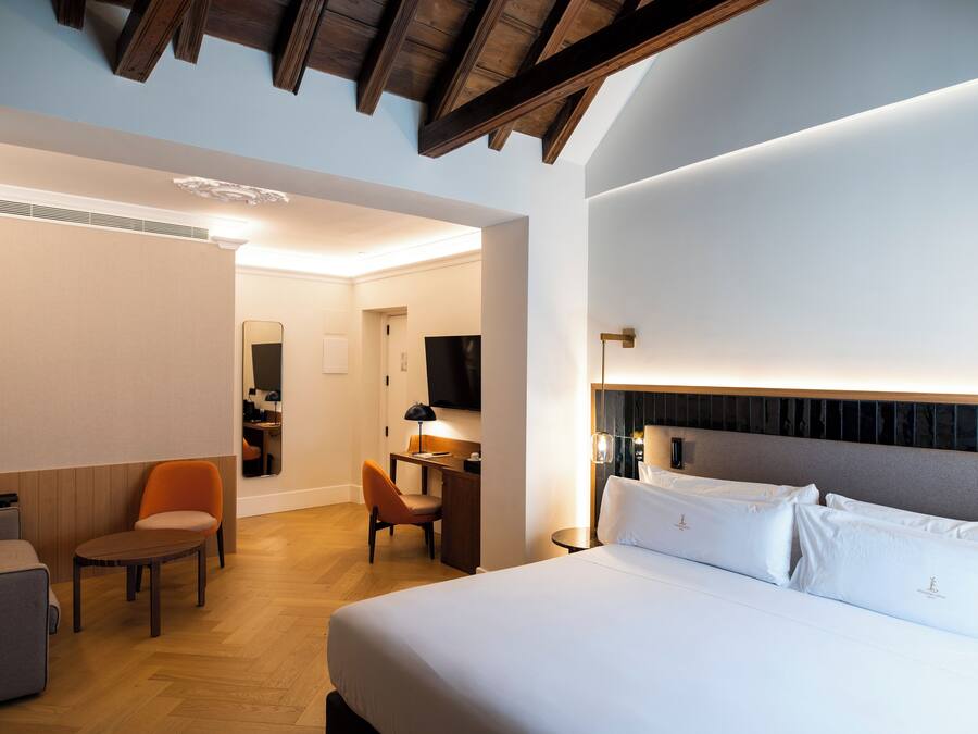 A hotel room with a large bed, a desk, a chair, and a television.