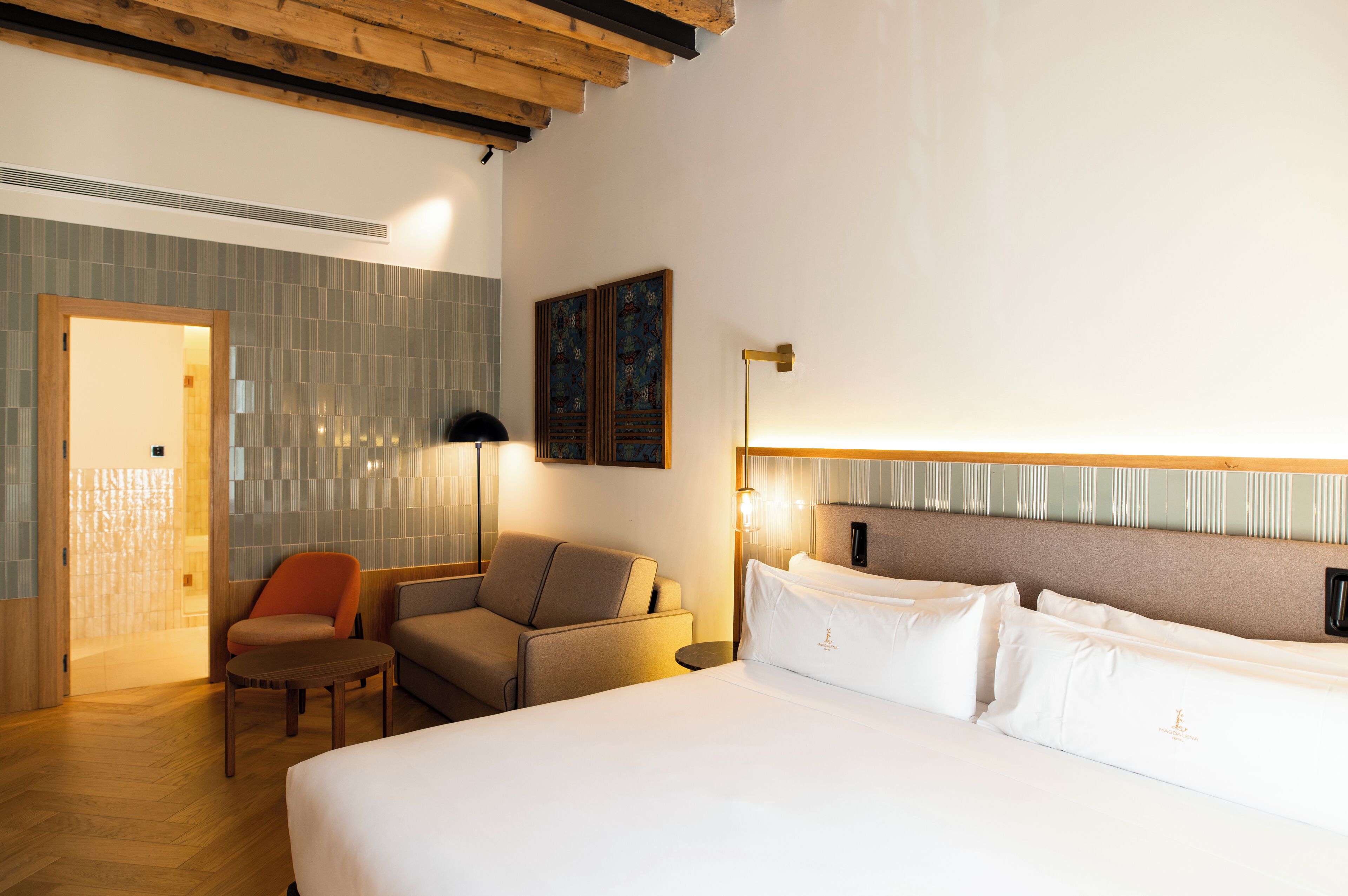 Habitación de hotel con una cama grande, un sofá, una silla y una obra de arte colgada en la pared.