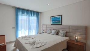 A modern bedroom with a large bed, a headboard, a bedside table with a lamp, and a window with curtains. - ★4 Bedroom, Holiday villa with Private Pool, Beach nearby in Albufeira (Albufeira)