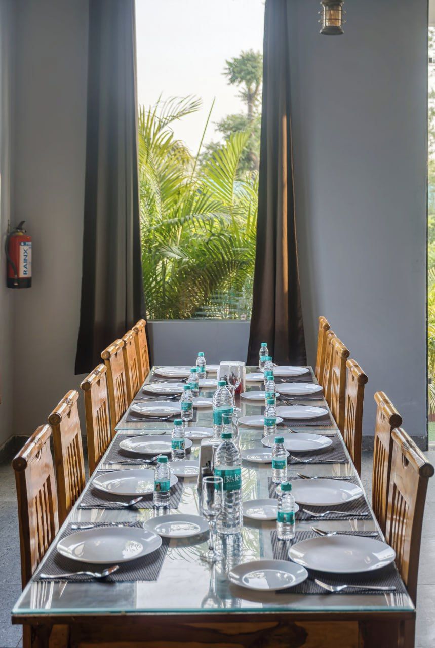 Una mesa de comedor preparada para una comida, con botellas de agua, platos y cubiertos.