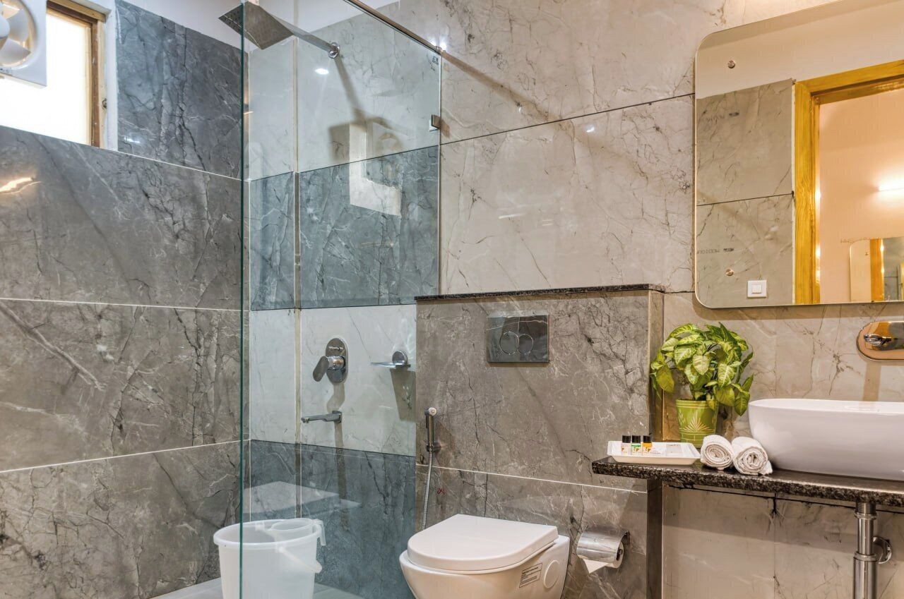 A modern bathroom with a glass shower enclosure, a toilet, a sink, and a mirror.