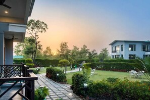 A hotel with a well-maintained garden, a clear pathway, and a modern building structure. - The Jungle Book Corbett (Ramnagar)
