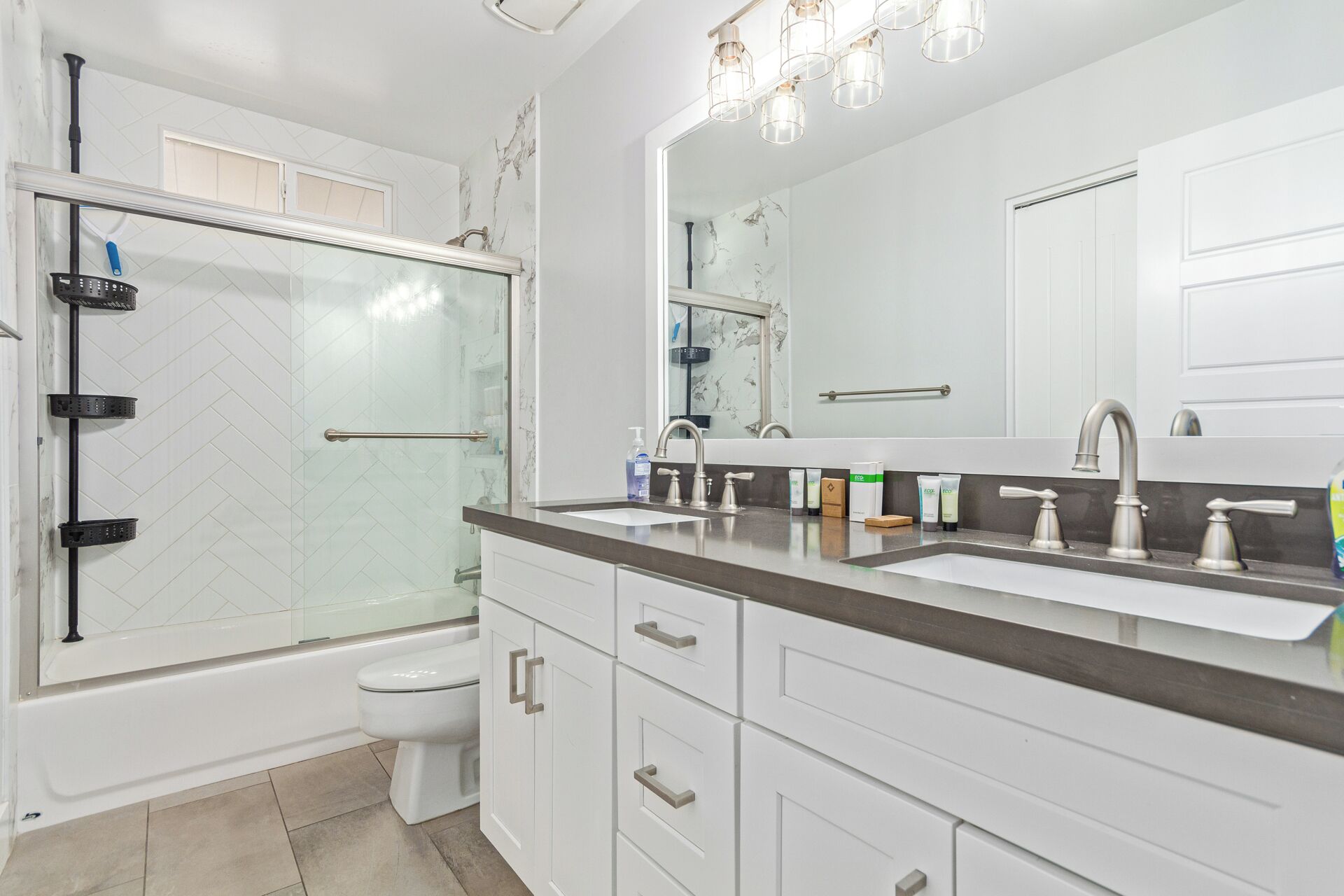 A modern bathroom with a glass-enclosed shower, a toilet, a double sink vanity, and a large mirror.