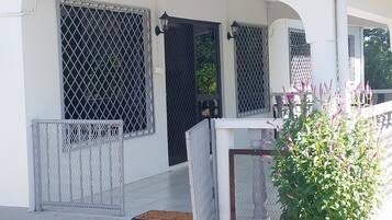 Guests can enjoy a covered porch with a table and a potted plant.