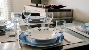 Mesa de jantar posta com pratos, copos e talheres.