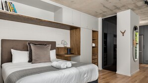 Ein modernes Schlafzimmer mit einem großen Bett, integrierten Regalen und einem begehbaren Kleiderschrank.