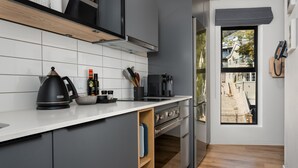 Eine moderne Küche mit grauen Schränken, einer weißen Arbeitsplatte, einem Wasserkocher und einer Kaffeemaschine.