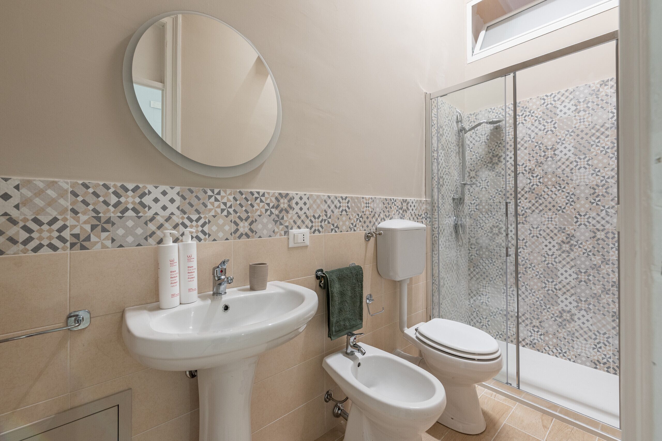 Ein Badezimmer mit Waschbecken, Bidet, Toilette und Duschbereich mit Glastür.