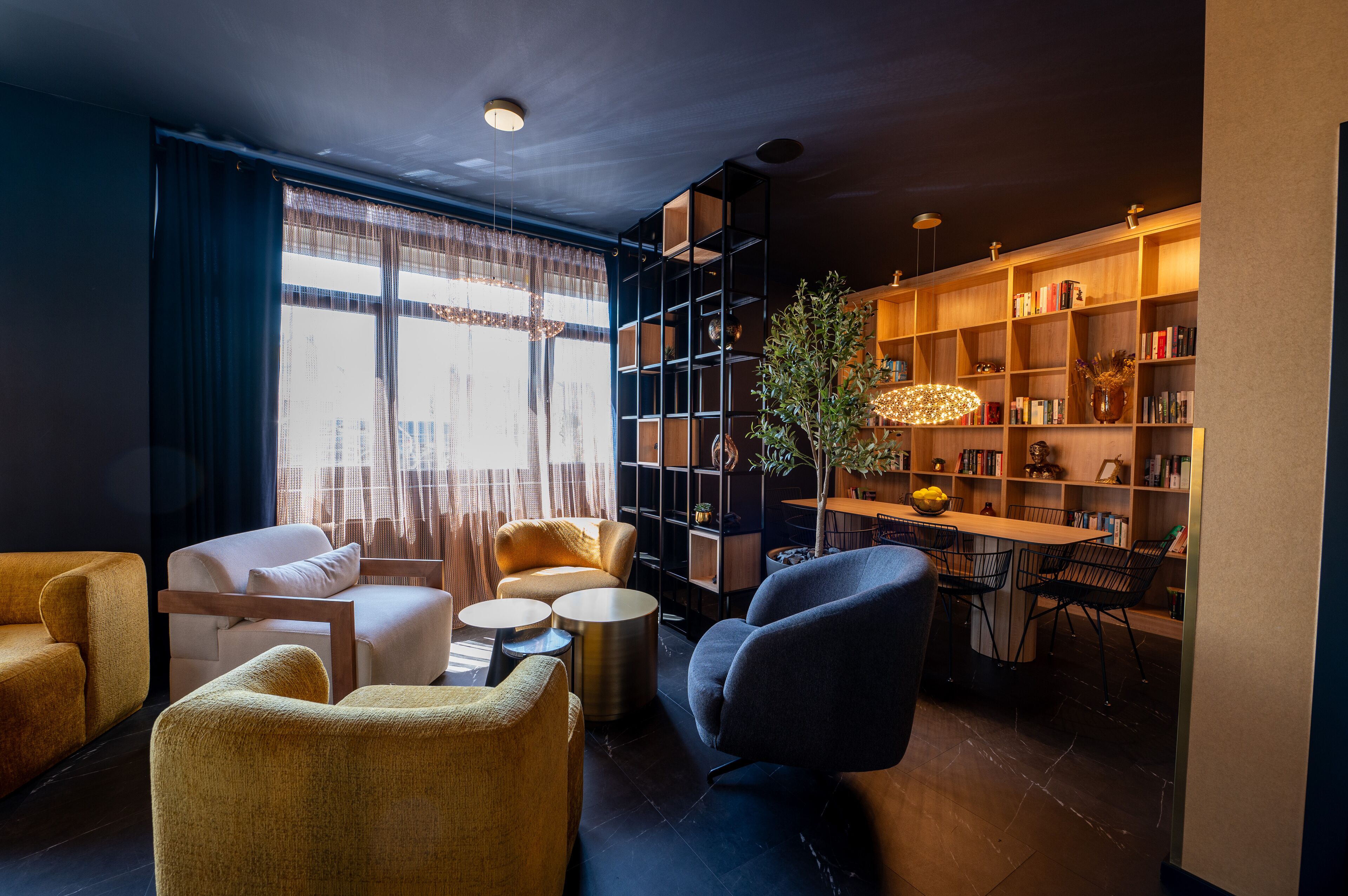 Una sala de estar moderna con un sofá, sillones, una mesita de centro y una estantería.