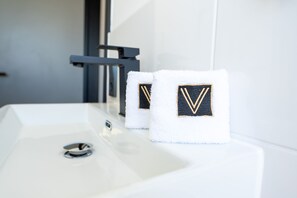 A white bathroom sink with two towels featuring embroidered monograms. - V Business Apartments Böblingen (Boeblingen)