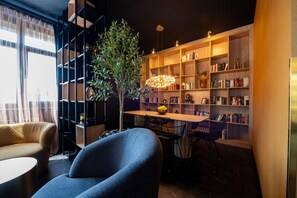 A modern living room with a bookshelf, a dining table, and a blue armchair. - V Business Apartments Böblingen (Boeblingen)