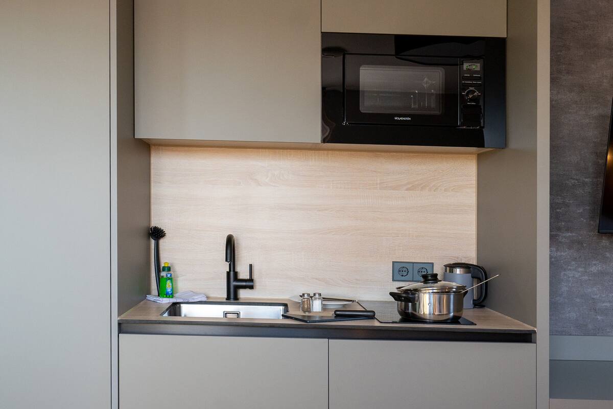 A compact kitchen with a microwave, sink, and cabinets.