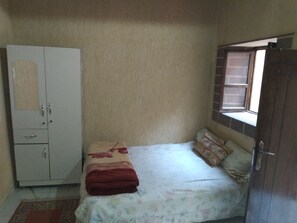 A bedroom with a bed, a wardrobe, and a window.