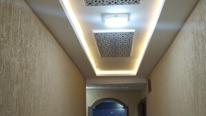A hallway with a decorative ceiling, a tiled floor, and a doorway leading to another room.