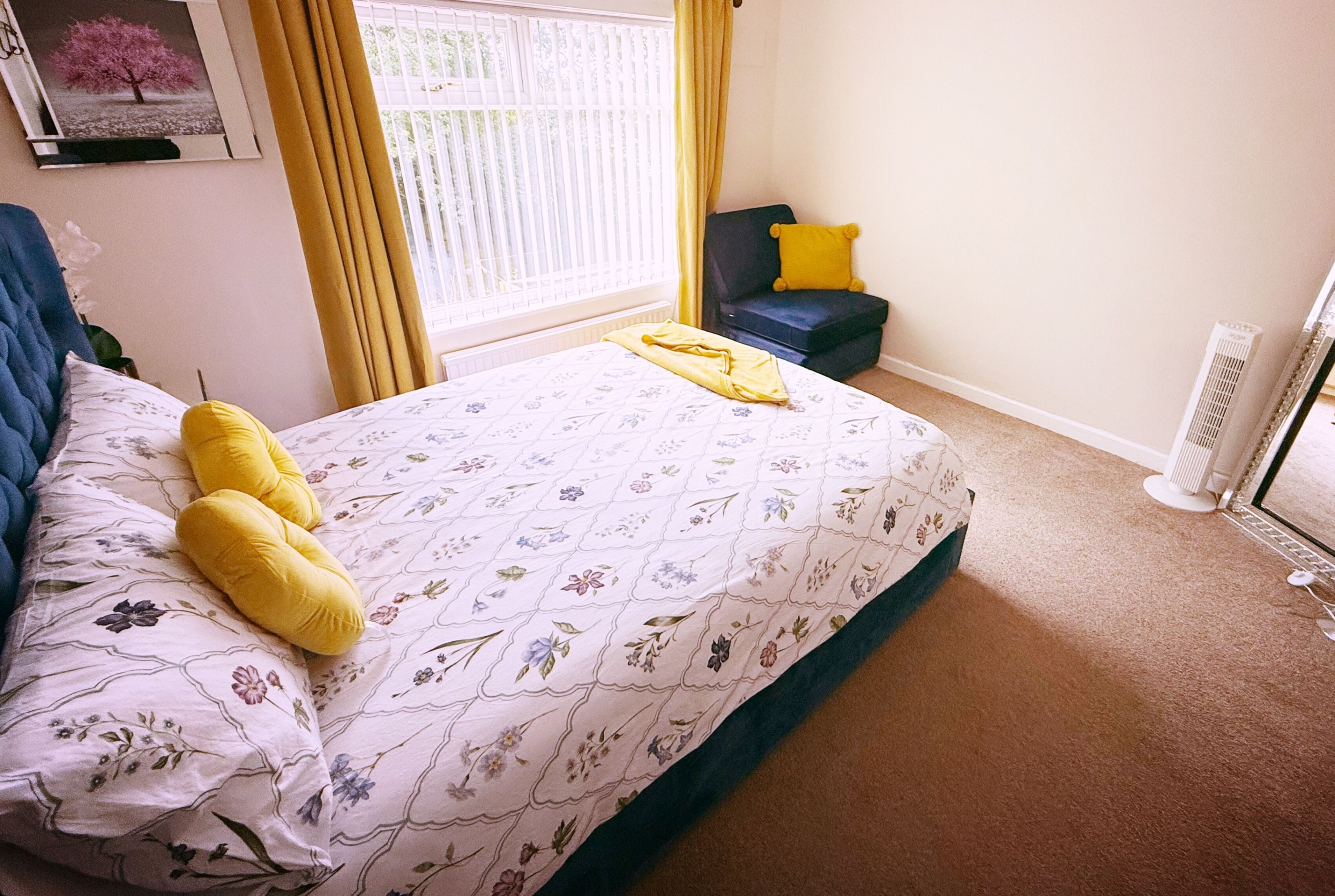 Ein Schlafzimmer mit Bett, Sessel, Heizkörper und einem Vorhangfenster.