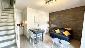 A compact living space with a dining area, a sofa, and a staircase.