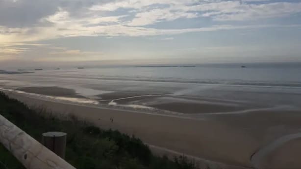 A beach with a wide sandy shore and a view of the ocean.