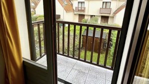 A balcony with a view of neighboring houses and a tiled patio.