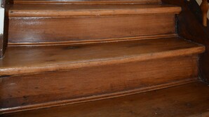 Eine Holztreppe mit Seilgeländer und einer Lampe am oberen Ende.